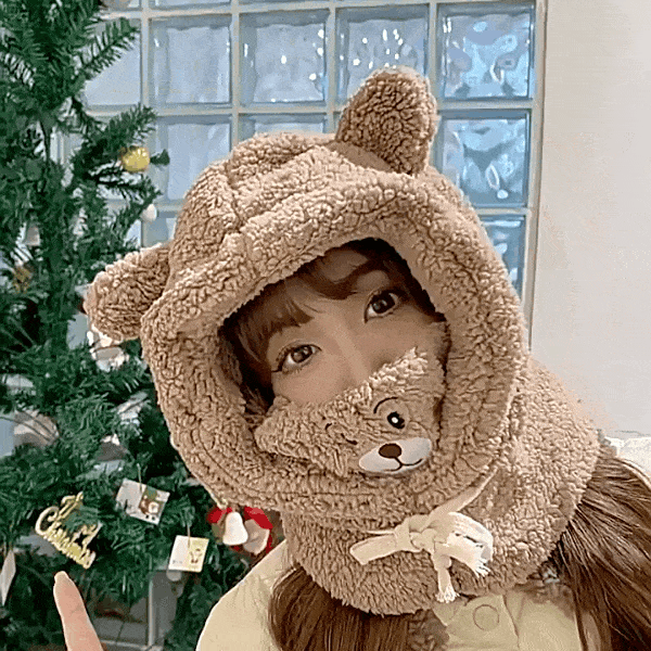 곰돌이 귀가 달린 브라운 컬러의 뽀글이 바라클라바를 쓰고 환하게 웃고 있는 여성 모델의 모습. 목 부분이 넉넉하게 설계되어 목도리 없이도 따뜻해 보이는 착용 이미지.